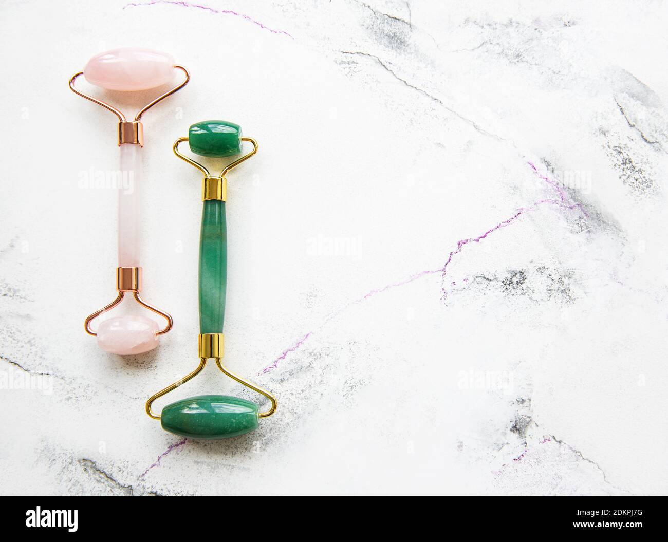 Jade face rollers for beauty facial massage therapy. Flat lay on white marble background Stock