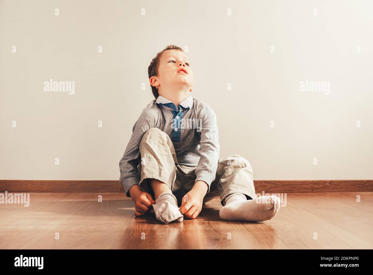 Boy Wearing Sock While Sitting On Hardwood Floor Stock Photo Alamy