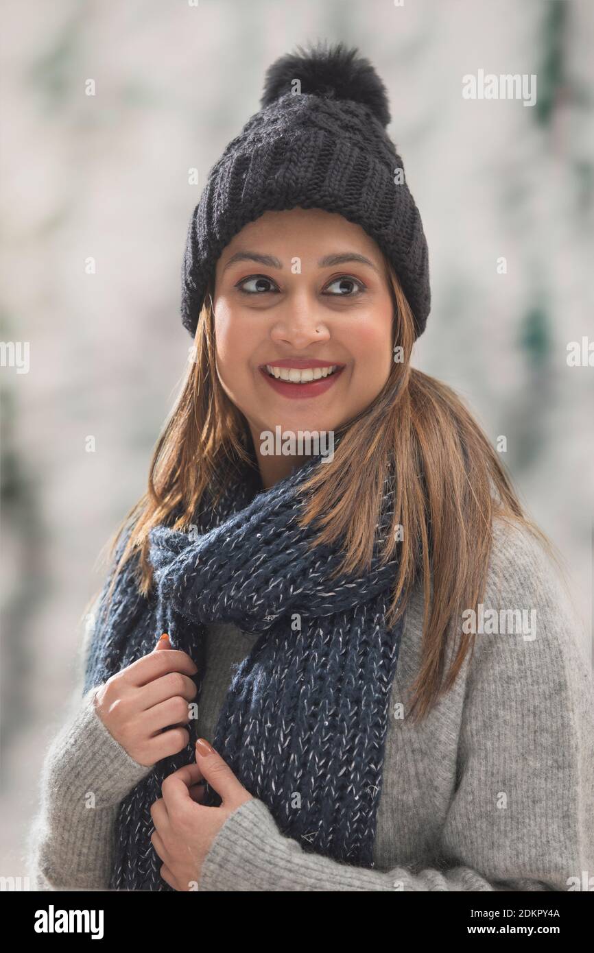 PORTRAIT OF A HAPPY WOMAN DRESSED IN WOOLEN CLOTHES LOOKING AWAY AND SMILING Stock Photo