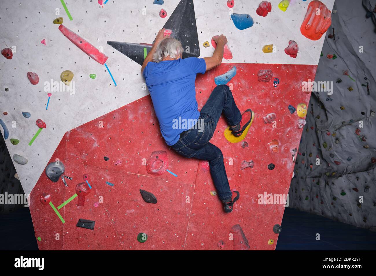 Professional senior man climbing on an artificial rock climbing wall