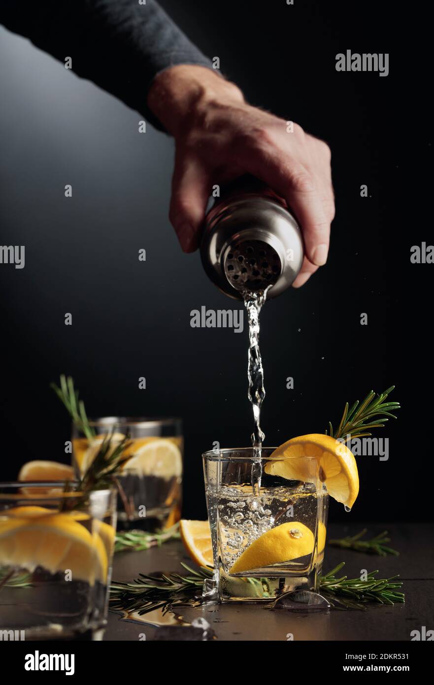 Cocktail Gin and Tonic with lemon and rosemary. The bartender pours a
