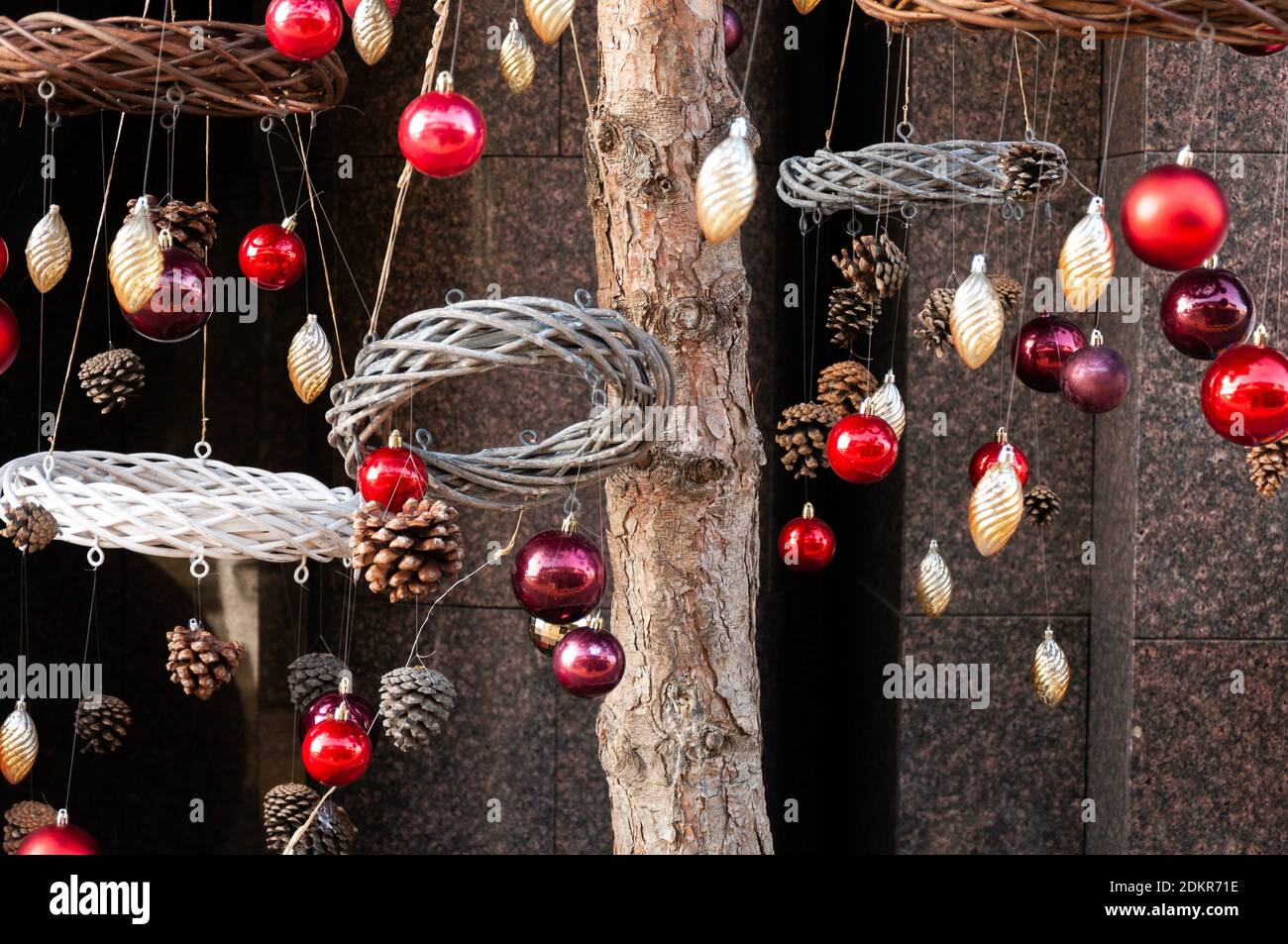 Christmas Baubles Balls and wreath hanging on pine tree branches outside Stock Photo