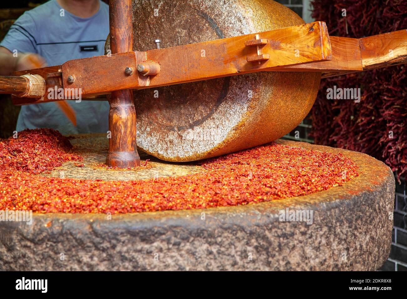 https://c8.alamy.com/comp/2DKR8X8/chinese-man-grinding-nuts-on-large-stone-wheel-in-street-food-shop-at-muslim-quarter-xian-xian-china-2DKR8X8.jpg