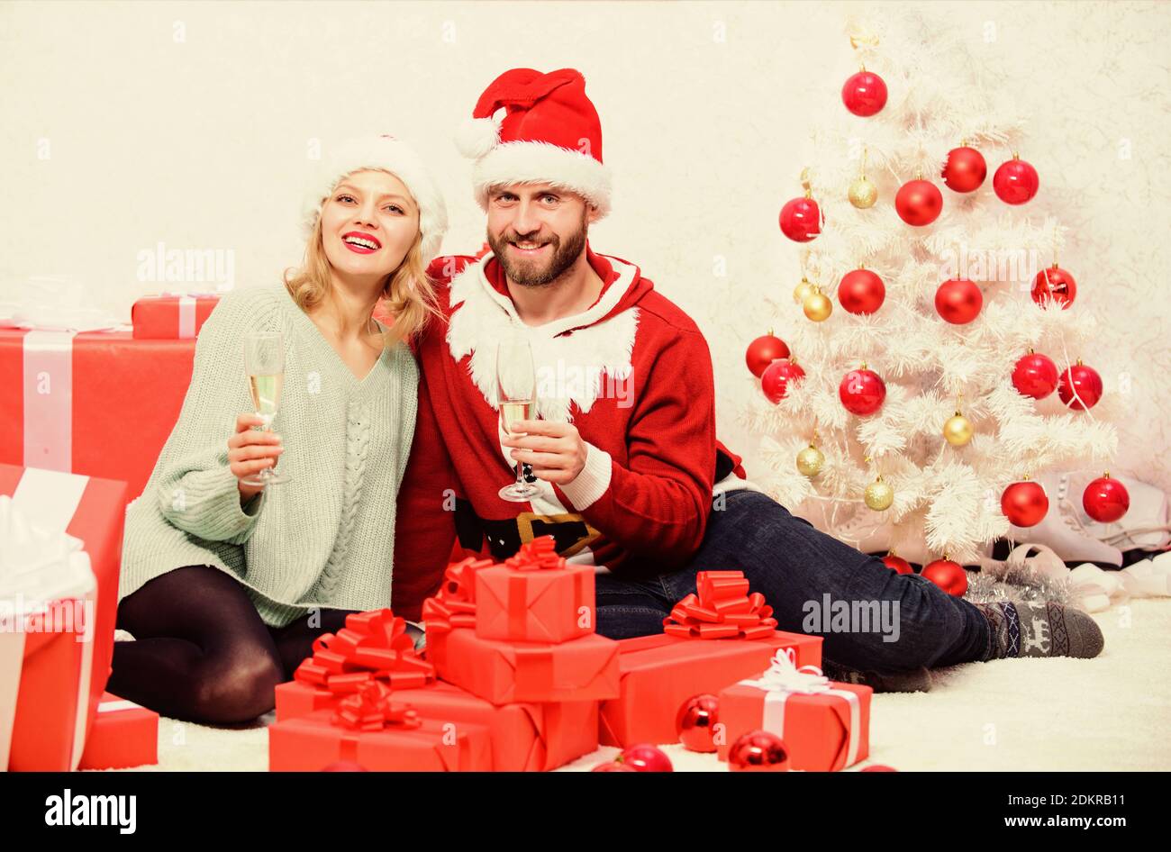 Couple wear hats as santa claus christmas tree background. Couple in love enjoy christmas celebration. It is easy to spread happiness around. Happy family celebrate christmas. Christmas fun concept. Stock Photo
