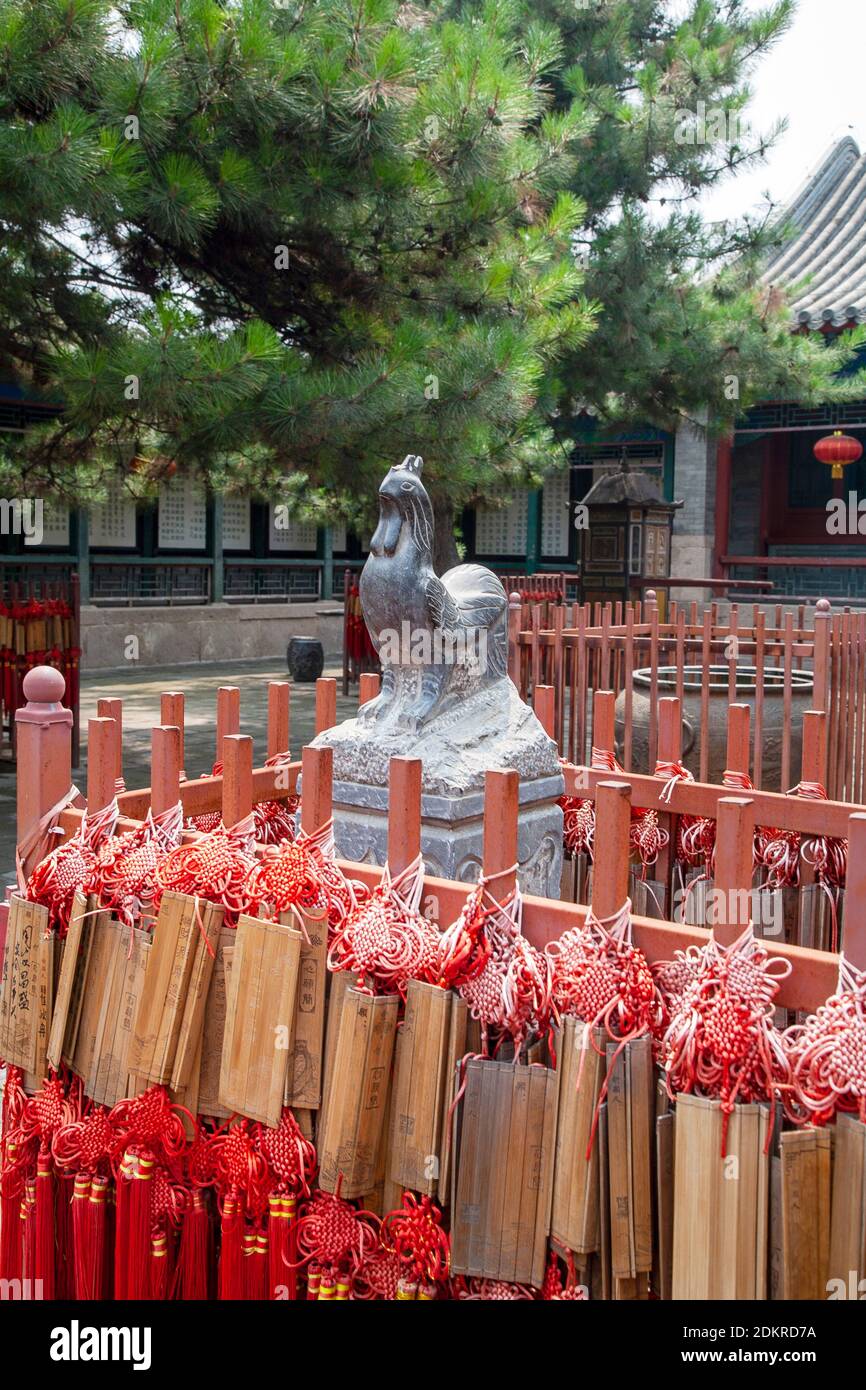 Red Chinese prayer sticks with statue for Year of the Rooster near Great Wall of China Beijing Stock Photo