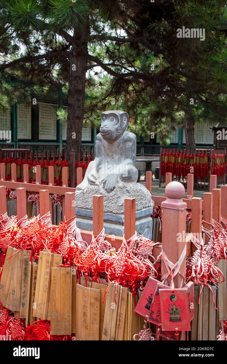 Red Chinese prayer sticks with statue for Year of the Monkey near Great Wall of China Beijing Stock Photo