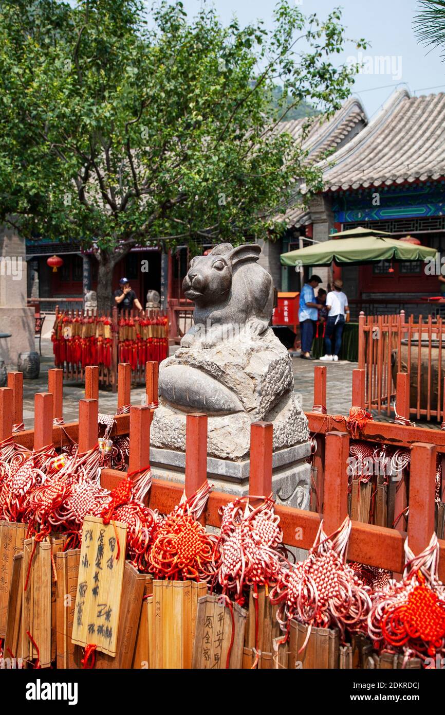 Red Chinese prayer sticks with statue for Year of the Rabbit near Great Wall of China Beijing Stock Photo