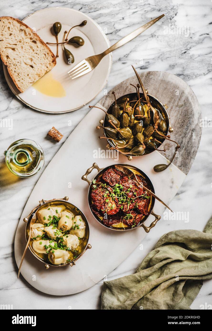 Flat-lay of different Mediterranean vegetarian meze in copper dishes, olive oil and fresh bread over marble table background, top view. Aegean cuisine concept Stock Photo