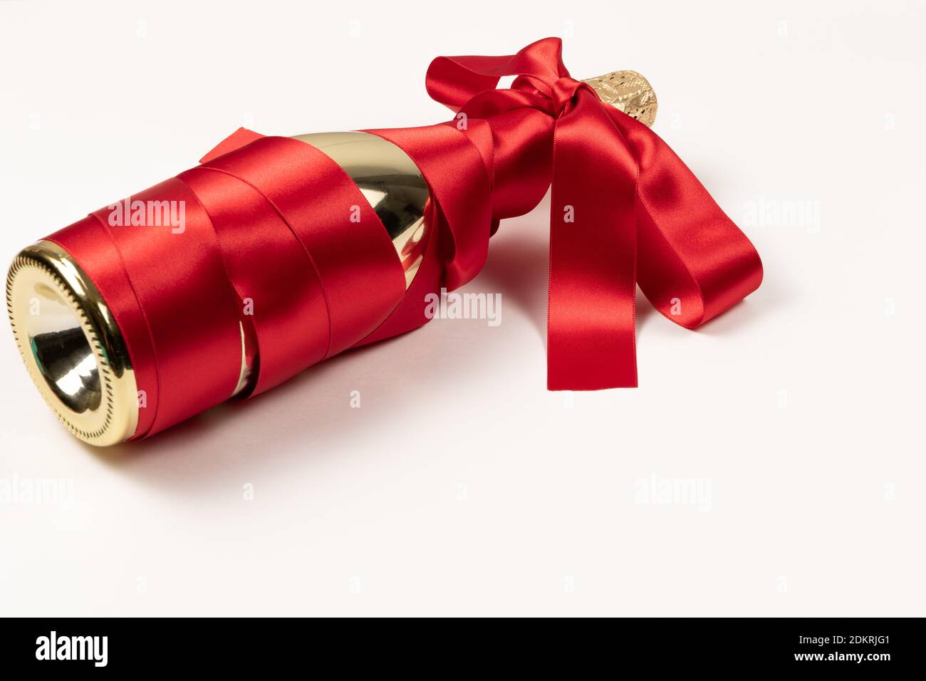 Gift box wrapped in gold wrapping paper, decorated with red raffia ribbon  and bow isolated on the white background Stock Photo