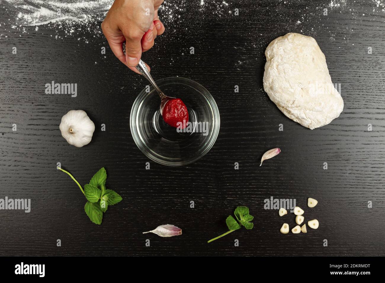 girl chef puts tomato paste in a bowl for making italian pizza at home