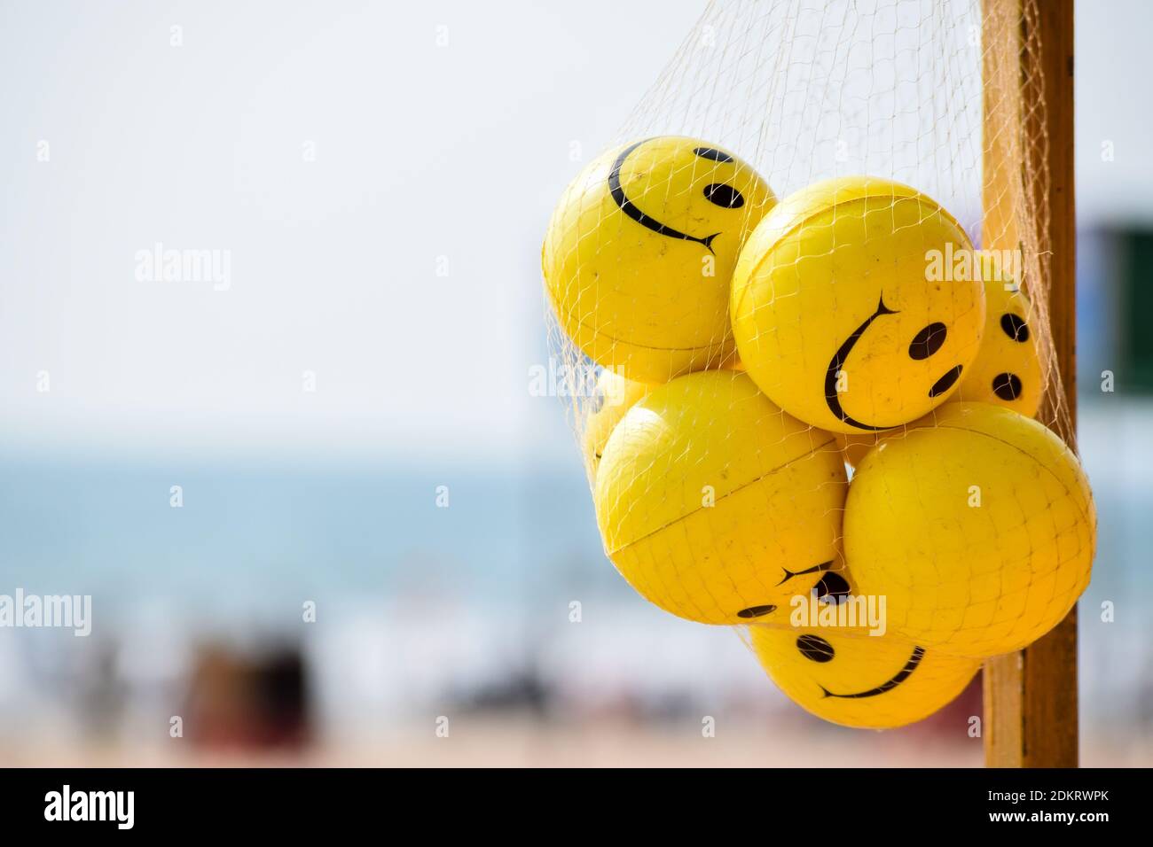 The bunch of Yellow-colored Stress reliever and hand exercise smiley balls on the beach hanging in the net bag. Stock Photo