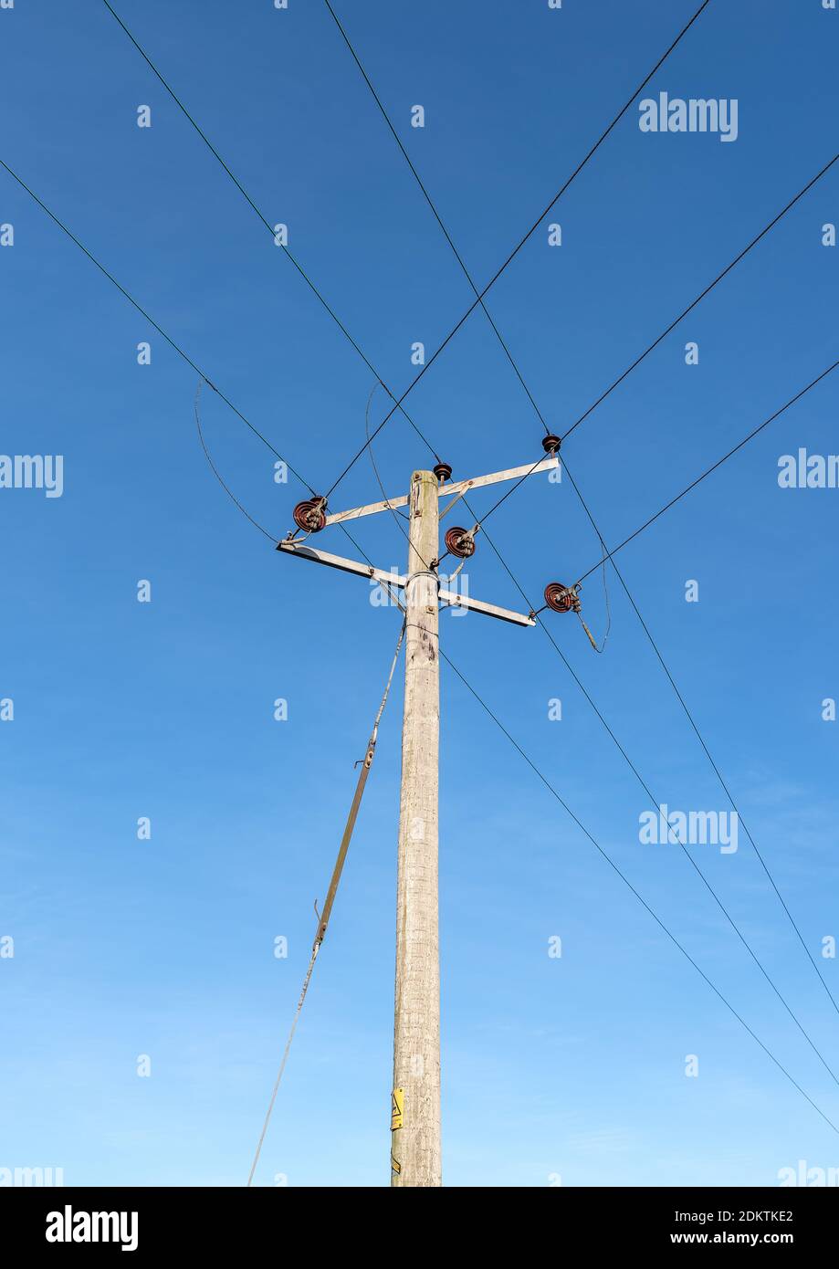 Wooden telegraph poles with wires and insulators against a clear blue sky background Stock Photo