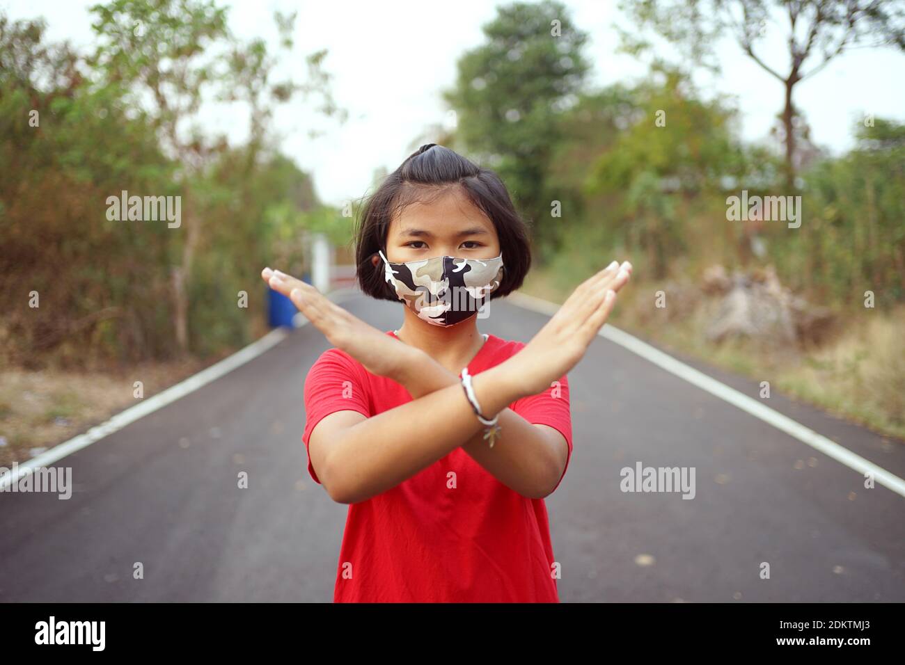 Portrait Of Girl Wearing Mask Gesturing While Standing On Road Stock Photo