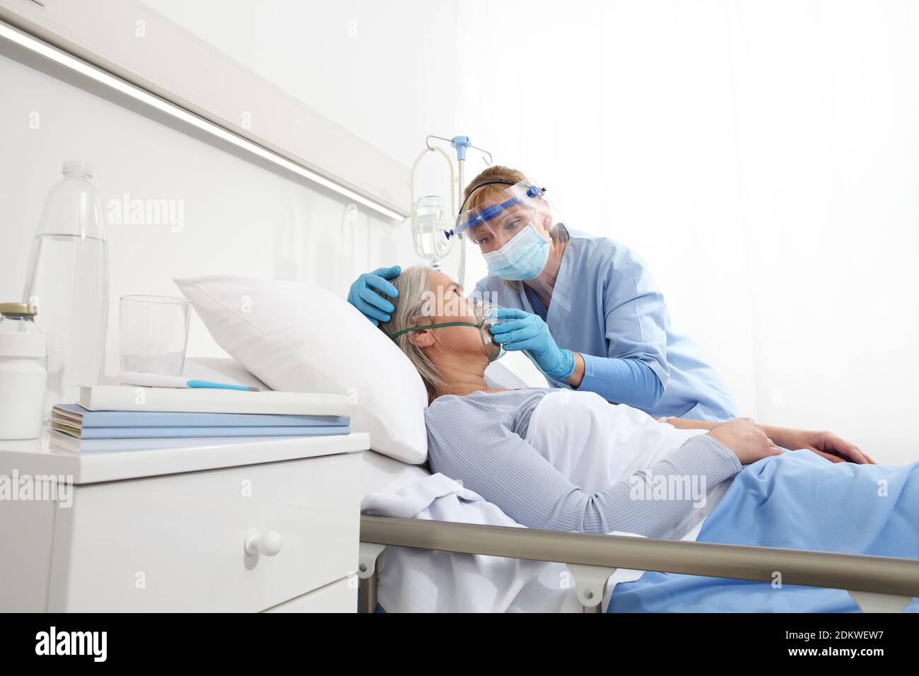 nurse puts oxygen mask on elderly woman patient lying in the hospital ...