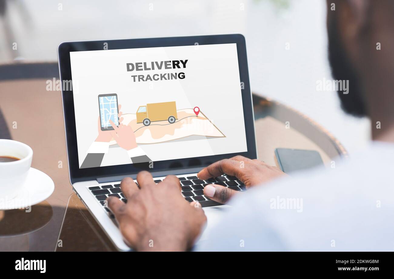 Black Man Using Delivery Tracking Service On Laptop While Sitting In Cafe Stock Photo