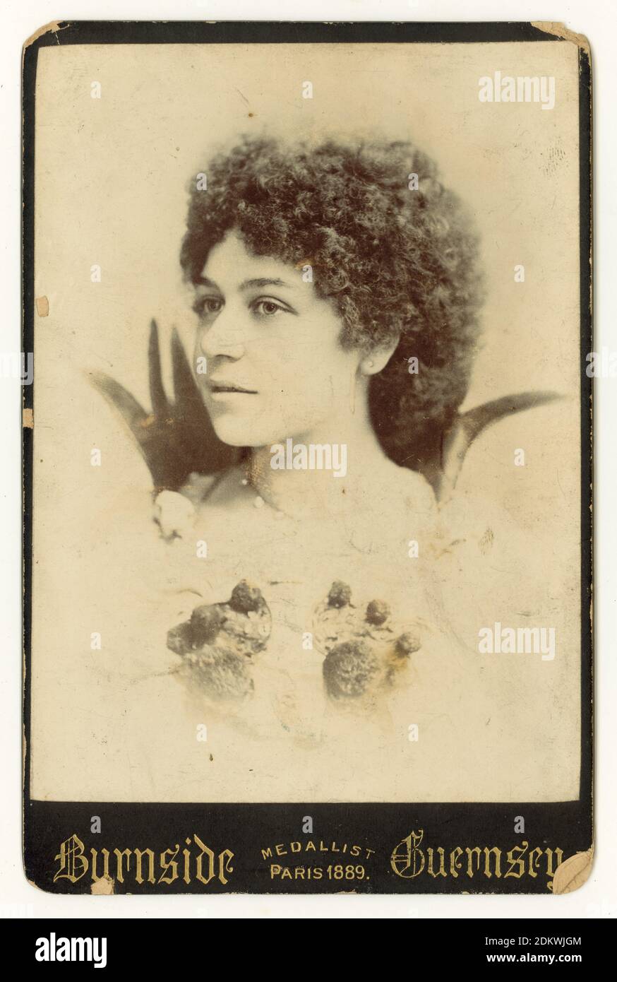 Original Victorian cabinet card of attractive young lady wearing fancy dress, ball gown, with curly hair. Fancy dress balls were very fashionable during the 1890's. She seems to be dressed as a flower. or maybe a strawberry. St Peter Port, Guernsey, Channel Islands, early 1890's Stock Photo