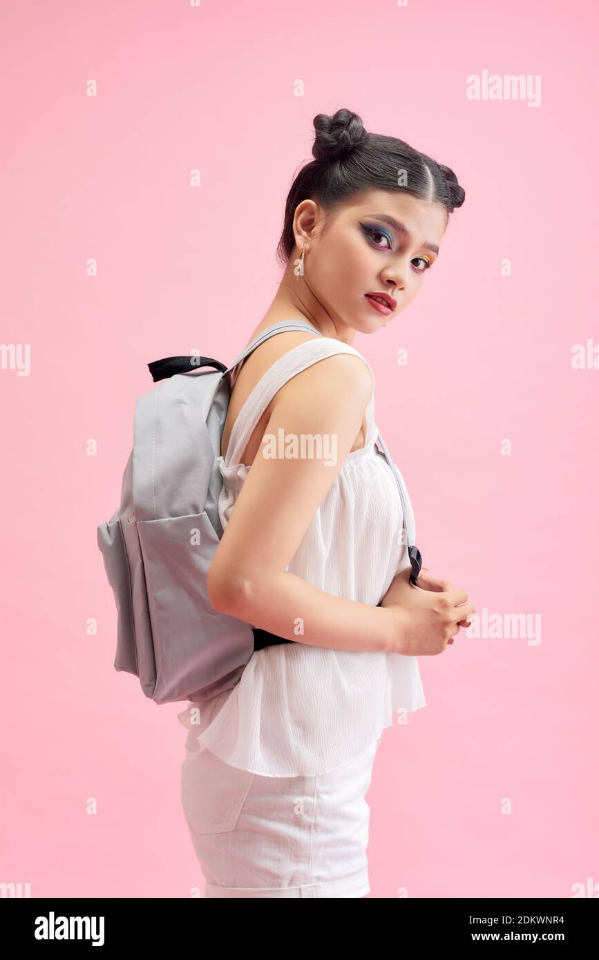 Fashionable schoolgirl girl holding a backpack behind her shoulders and