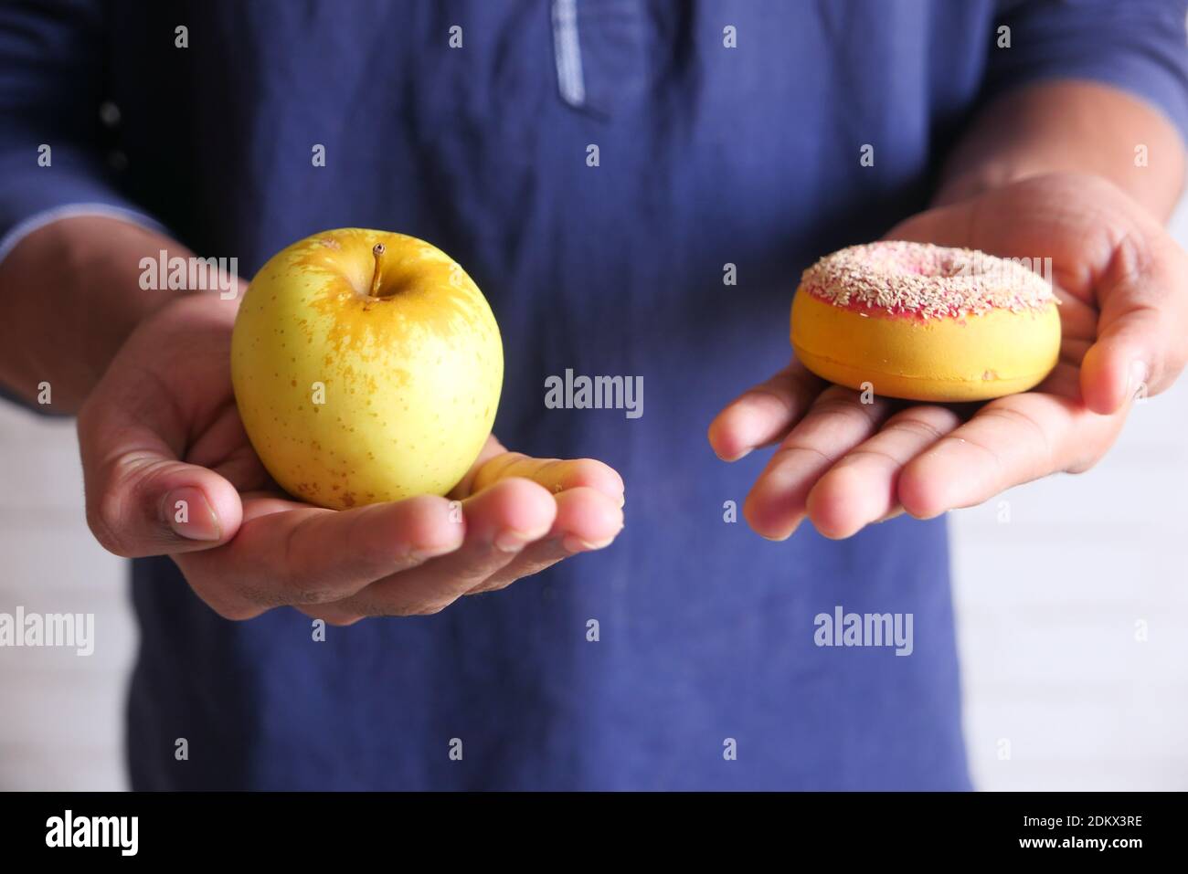 hand holding donuts and apple on hand close up  Stock Photo
