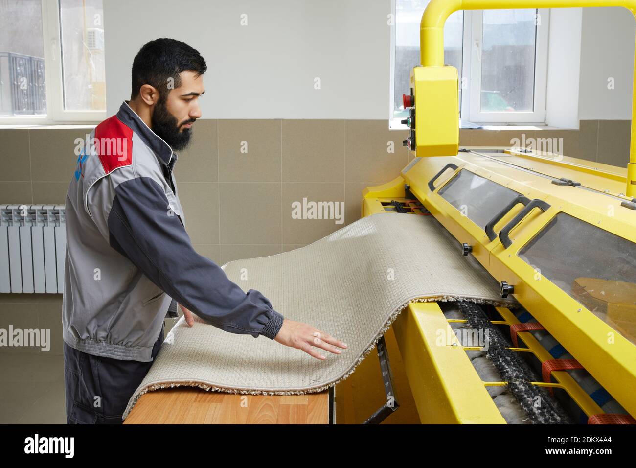 Man operating carpet automatic washing machine in professional laundry service Stock Photo