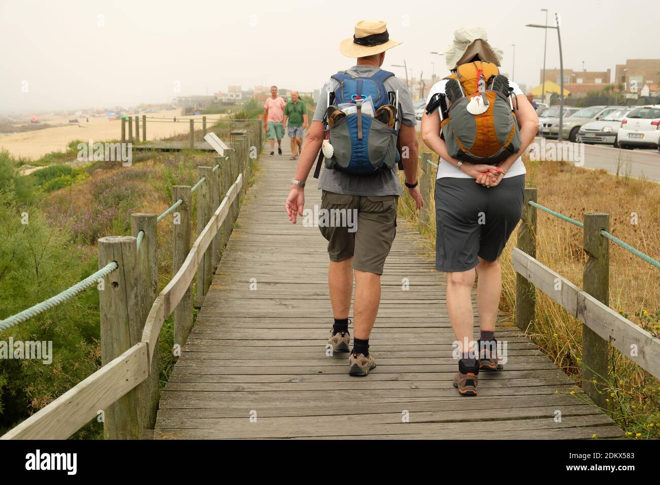 A couple of pilgrims walking on a boardwalk during their pilgrimage along the Camino de Santiago Portugués (Portuguese Way of Saint James). Stock Photo
