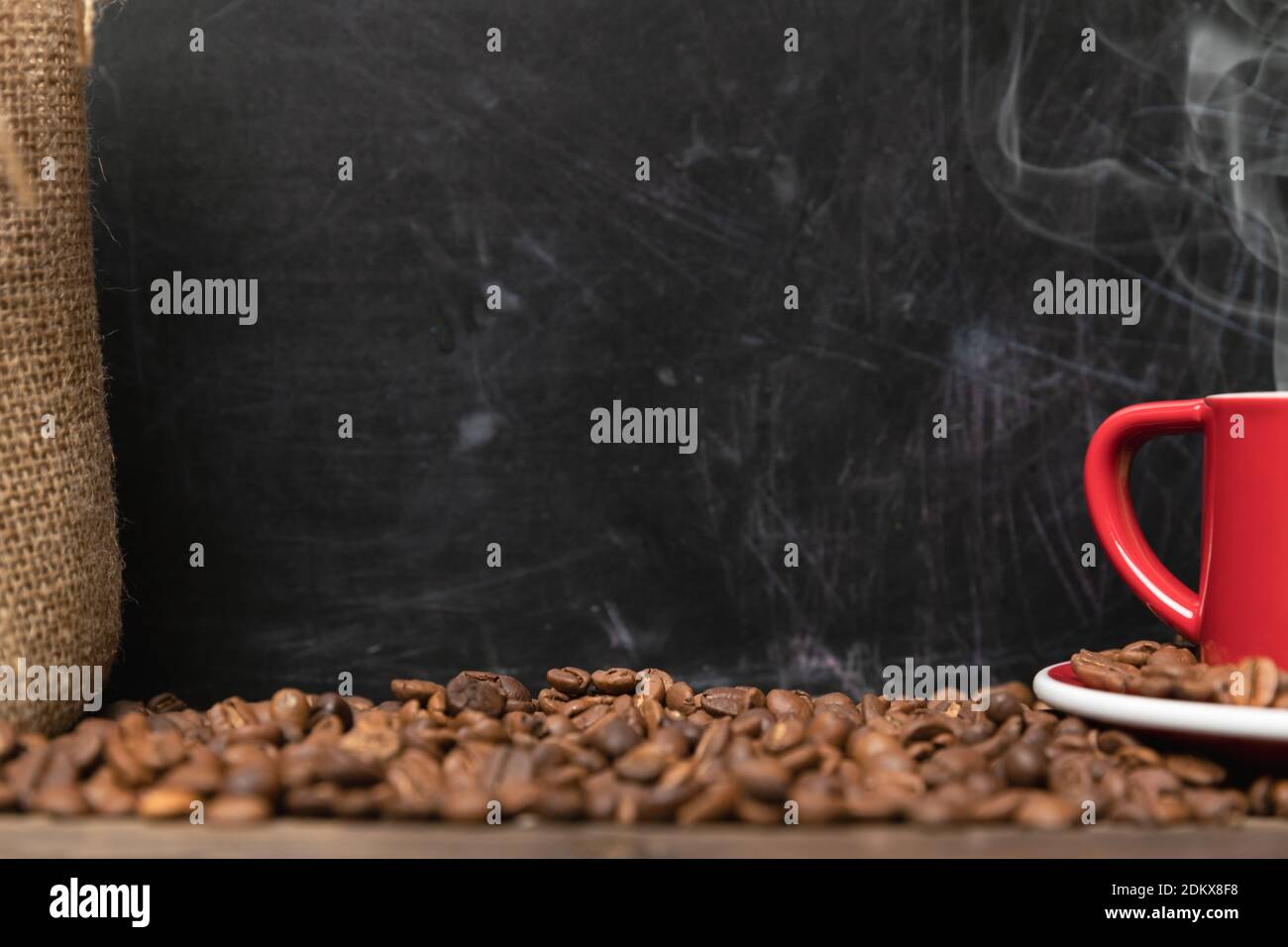 Red cup of coffee with coffee beans on dark textured background with copy space. Morning fresh energy concept. Stock Photo