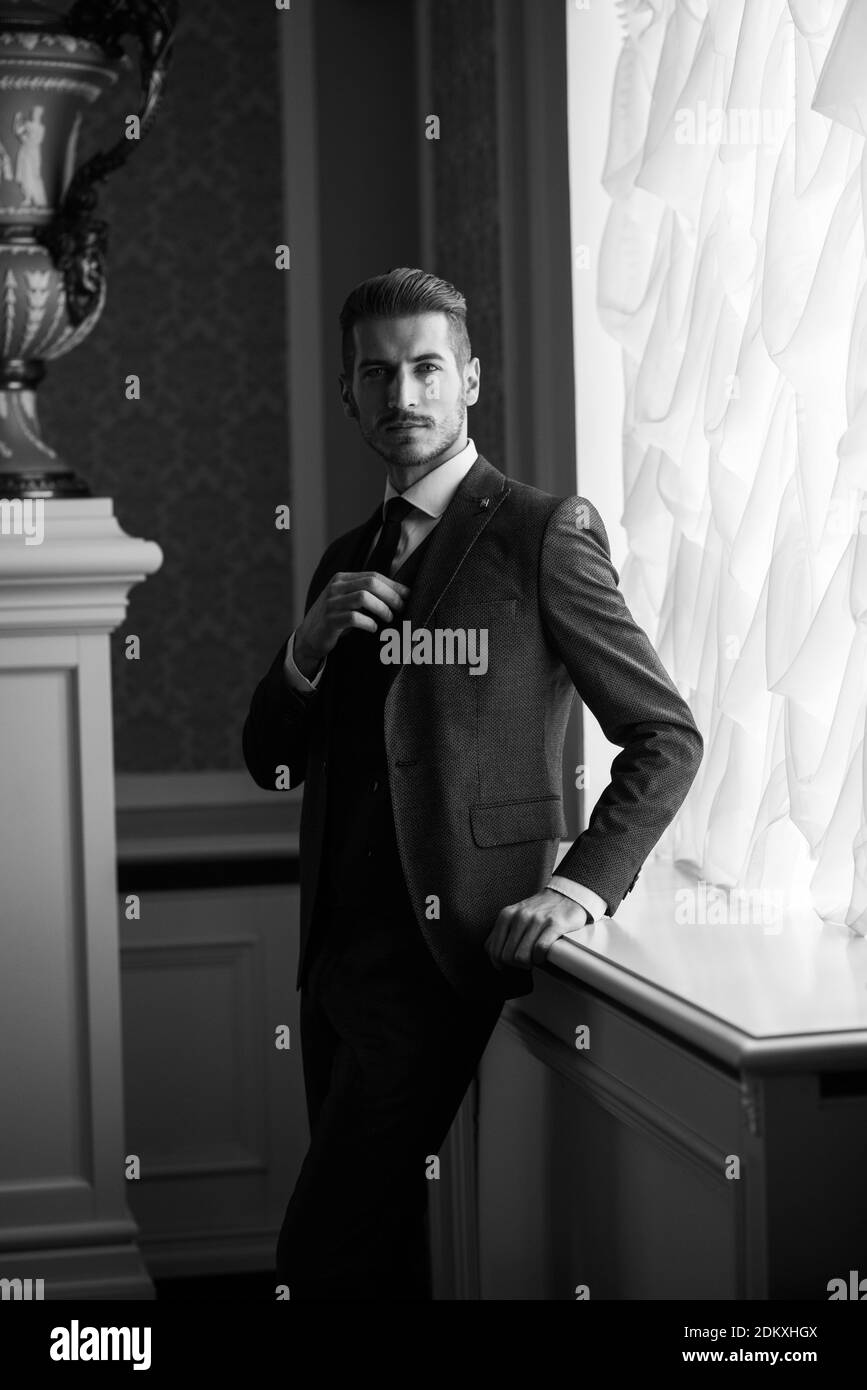 Groom at wedding day smiling and waiting for bride in the hall of the hotel. Elegant rich man in costume and bow-tie. Stock Photo