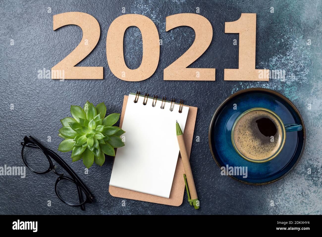 New year 2021 and notebook on desk. 2021 template with open notebook, coffee cup, eyeglasses, plant succulent on blue background. Goals, plan, strateg Stock Photo