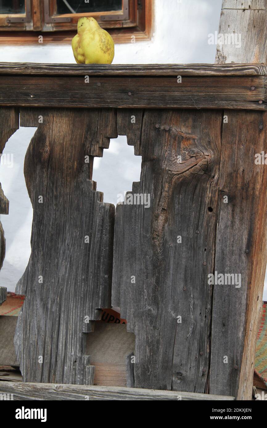 Vrancea County, Romania. Carved wooden porch of an old traditional house. A quince on the top rail. Stock Photo