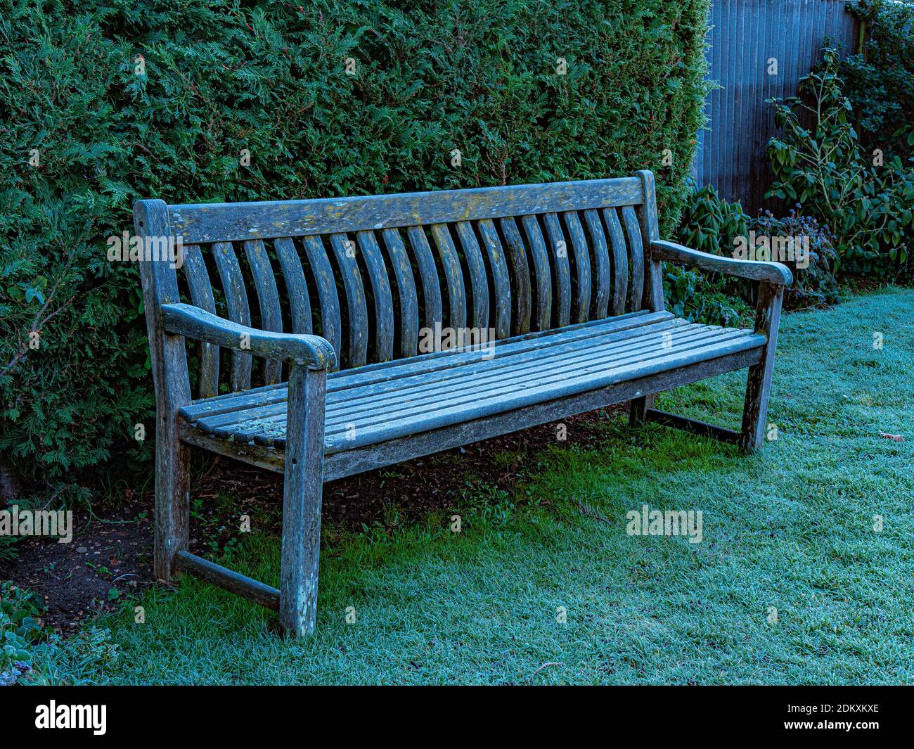 Closeup of early morning winter frost on an old wooden bench, outdoors in a garden / yard / park. Stock Photo