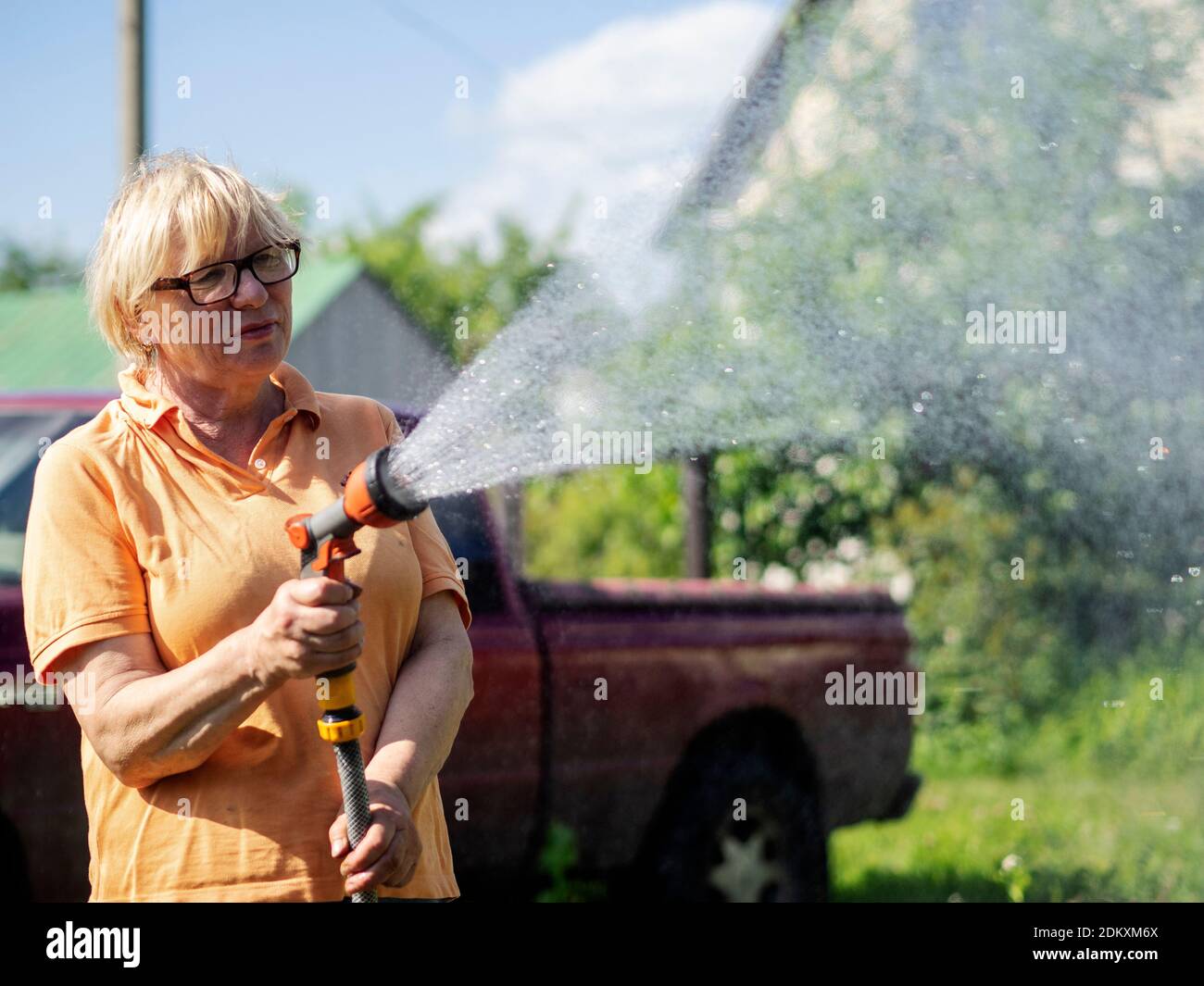 Woman Spraying Water On Plants Stock Photo Alamy
