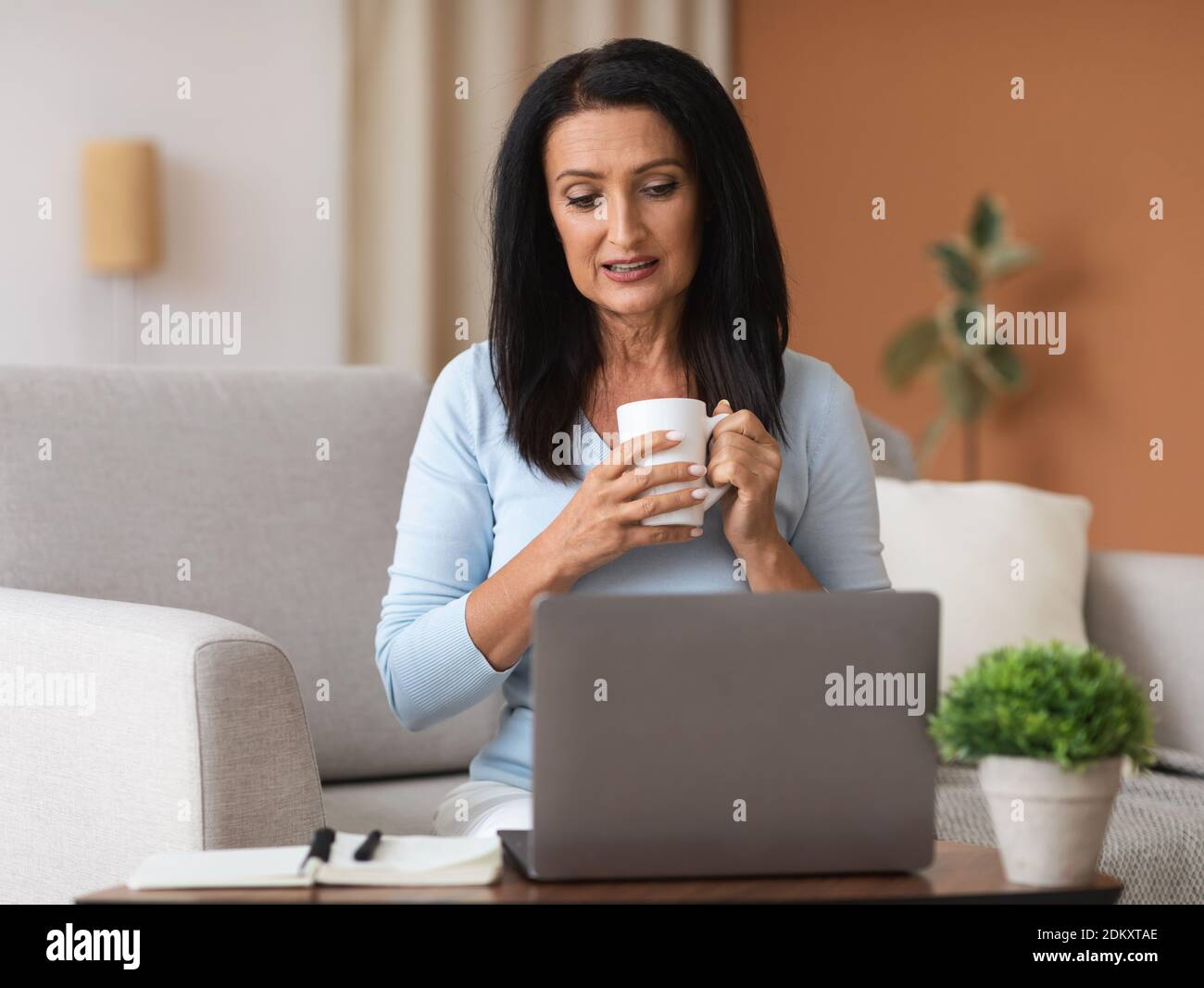 Mature woman sitting on sofa hi-res stock photography and images - Alamy