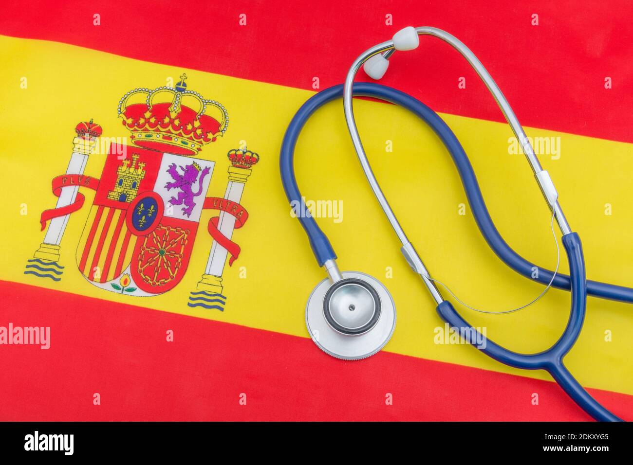Medical stethoscope on small fabric Spanish flag. Metaphor poorly