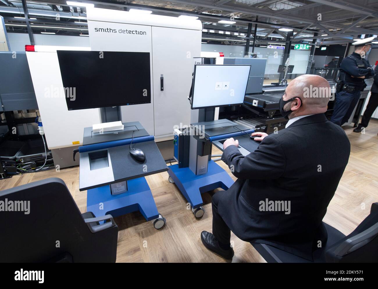 14 December 2020, Hessen, Frankfurt/Main: A security employee simulates the function of a CT luggage scanner in passenger handling at Frankfurt Airport. The devices are supposed to be able to record the contents of flight baggage three-dimensionally within the shortest possible time and to detect hazardous substances largely automatically. (To dpa 'Federal police tests CT luggage scanner at airport' of 16.12.20) Photo: Boris Roessler/dpa Stock Photo