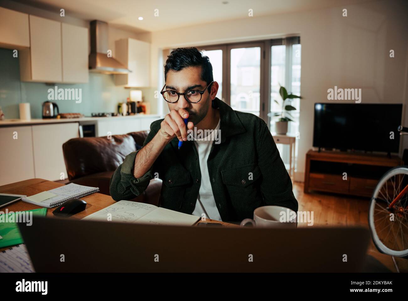 Mixed race business man wearing spectacles studying off desktop computer attending online meetings Stock Photo