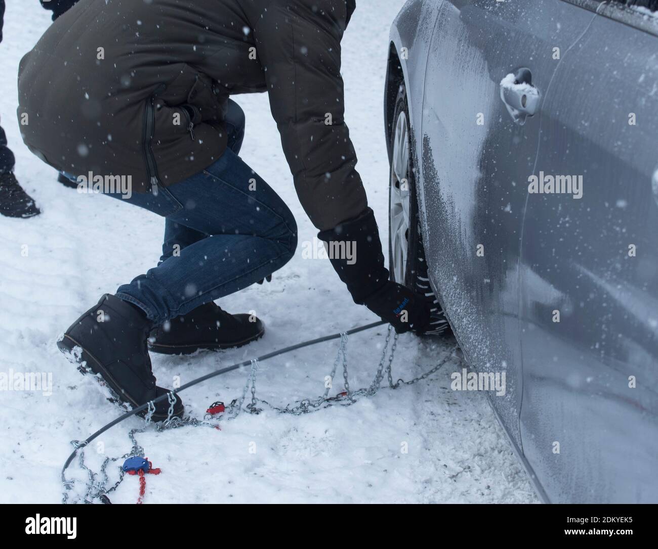 putting on snow chains on a car, road safety in winter Stock Photo Alamy