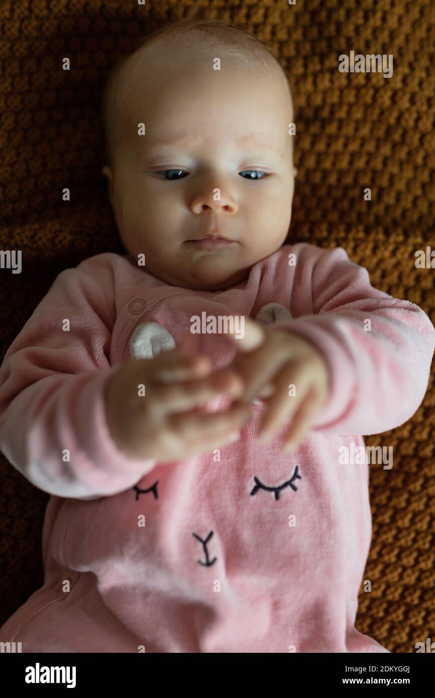 Caucasian blonde baby four months old lying on cozy knitted blanket at