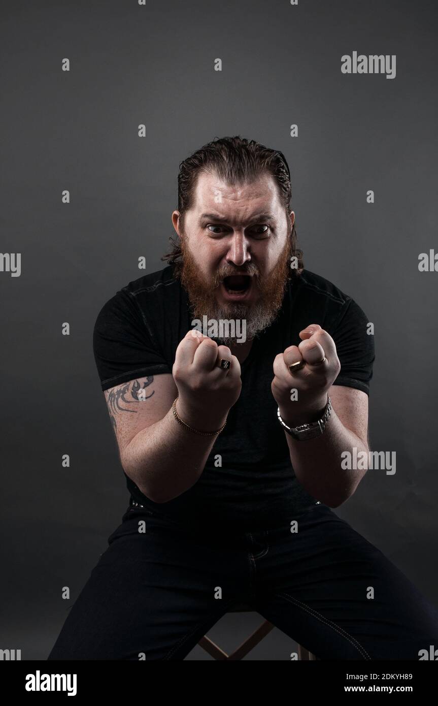 Angry Mid Adult Man Clenching Fist While Sitting Against Black