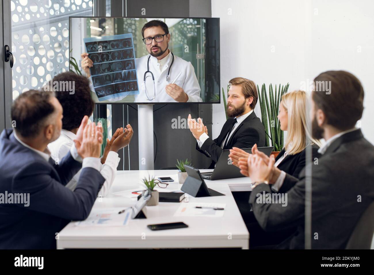 Front view of five multiracial business people, healthcare experts, discussing cost efficiency of treatment plan of patient while having video Stock Photo