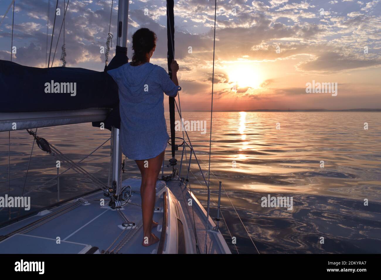 Woman relaxing on sailboat during serene sunset at sea Stock Photo