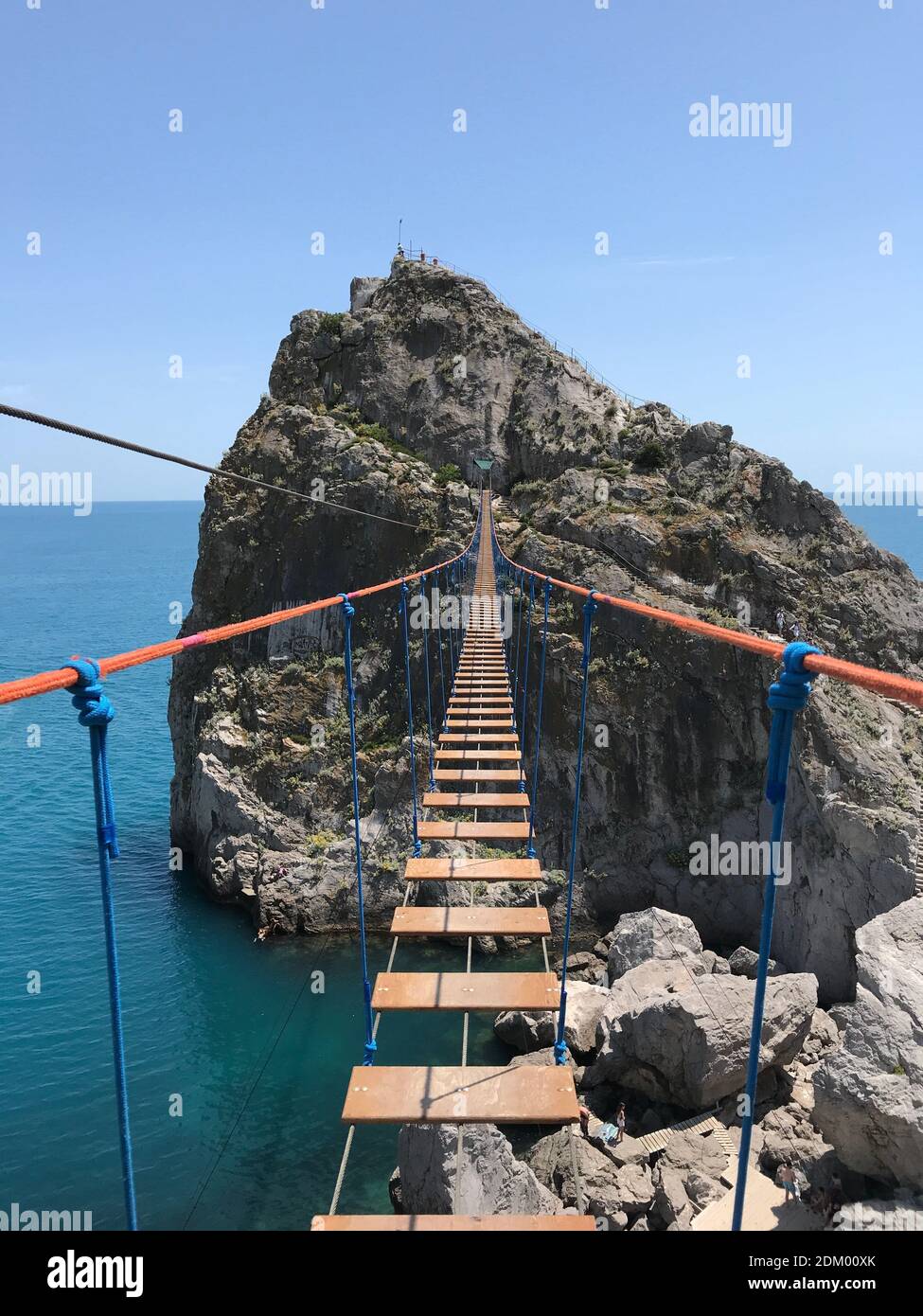 Dangerous wooden bridge hanging over the water in summer. Risky hiking adventure to beautiful travel destination Stock Photo