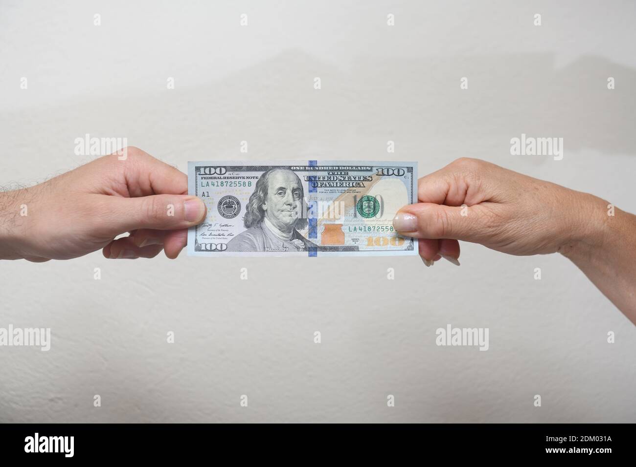 Human hands pulling a one-hundred-dollar bill Stock Photo