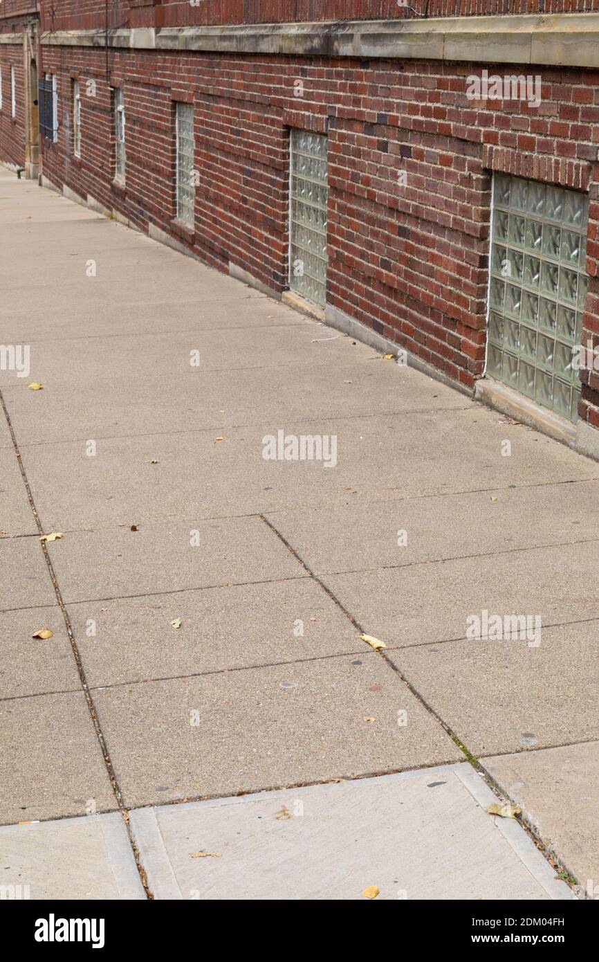 Angled view of a brick building and sidewalk with basement windows filled with glass brick