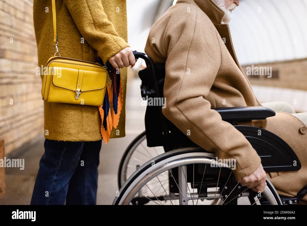 cropped view of woman holding wheelchair of senior disabled man on metro station Stock Photo