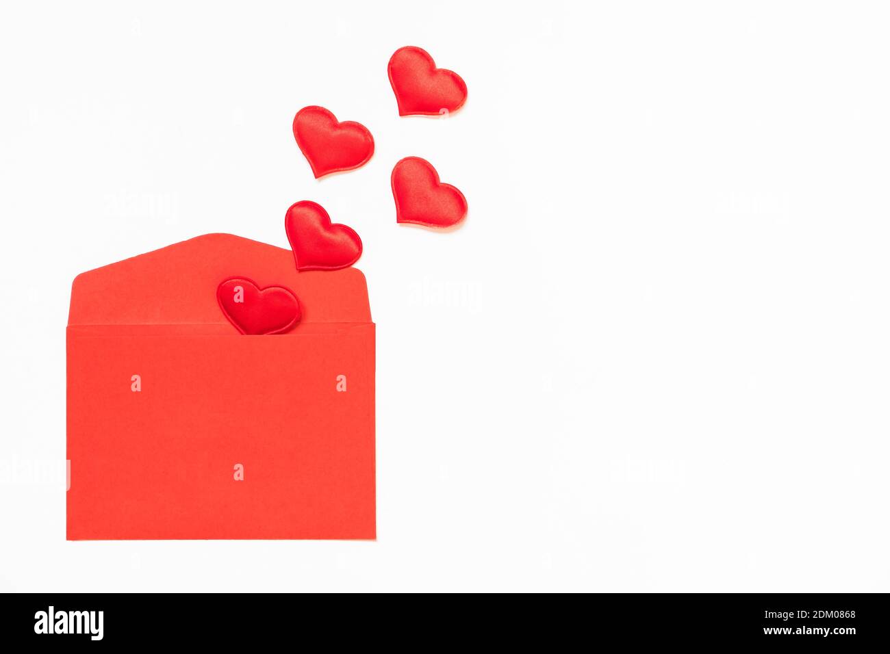 Opened red envelope and many hearts on a white background with copy space. Stock Photo