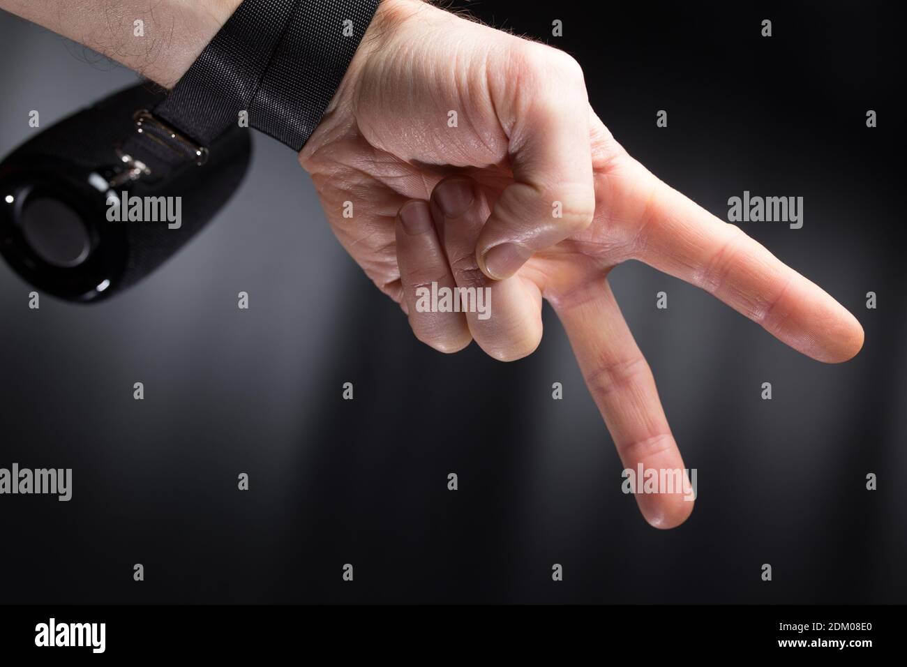 Hand make victory sign holding wireless speaker on black background with copyspace. Stock Photo