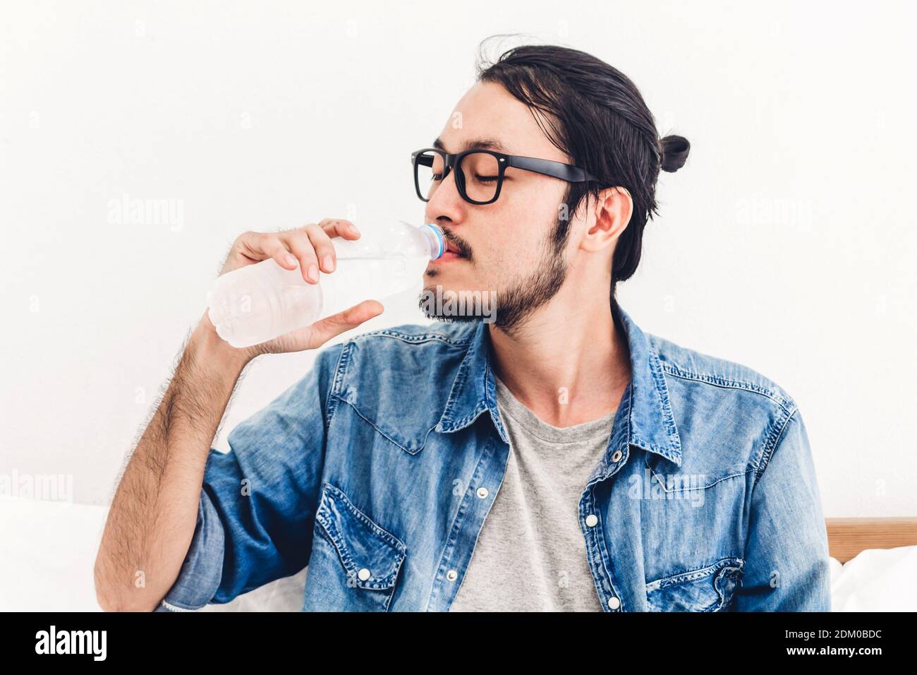Man Wearing Eyeglasses Drinking Water Against White Background Stock
