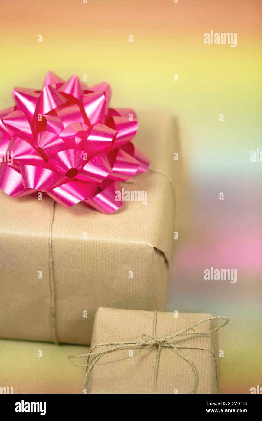 Two Gift boxes wrapped in plain brown paper with pink decoration and rainbow background, present for birthday or Valentine's day, mother's day Stock Photo