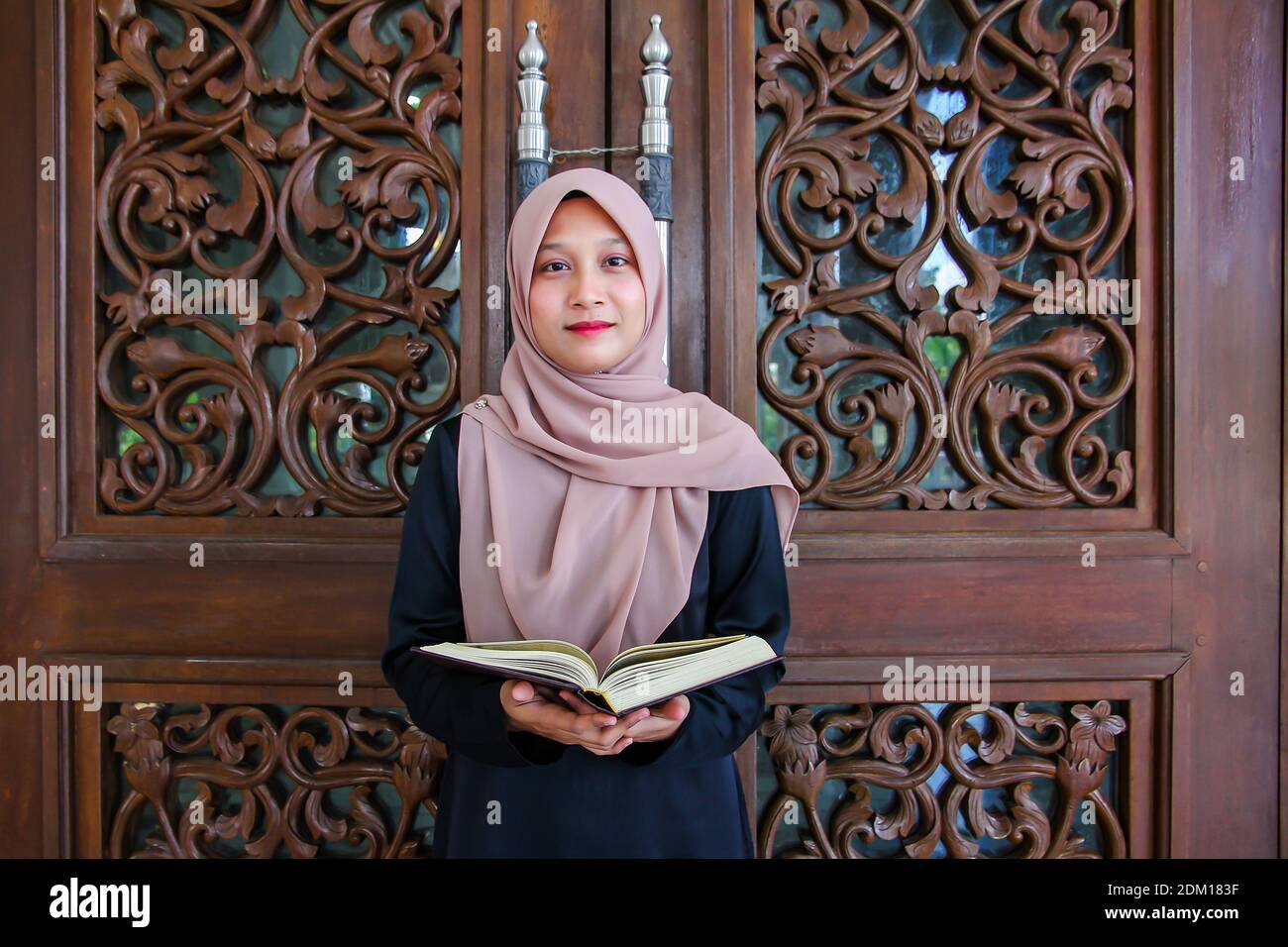 Portrait Of Woman Wearing Hijab While Reading Holy Book Against Wood ...