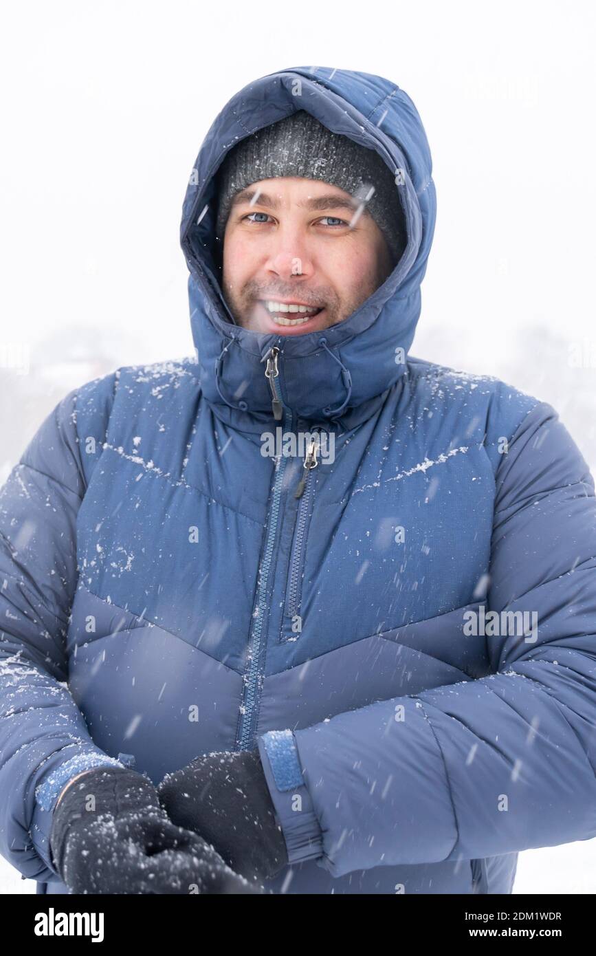 40s portrait of smiling man in winter clothes in heavy snow Stock