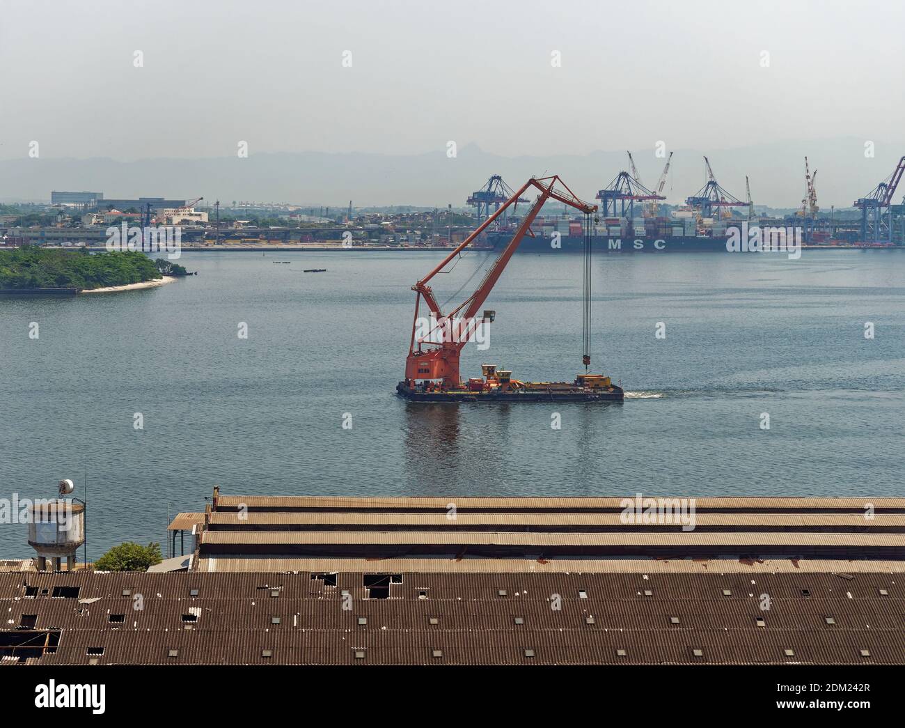 A Floating Crane sails slowly in to the Old Port of Rio de Janeiro at Porto Atlantico, pas the old warehouses which are being demolished. Stock Photo
